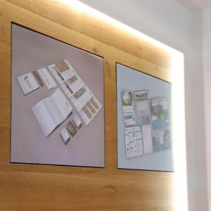 Holzwand mit eingelassenen Bilderrahmen, mit Visualisierungen der Federleicht Projekte